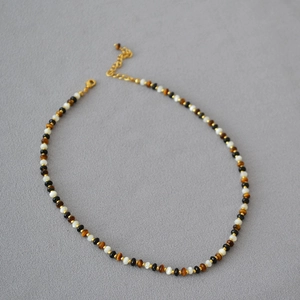 Close-up of tiger eye stone and black onyx beaded necklace with gold spacers and lobster clasp
