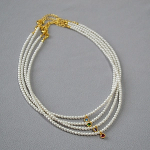 Close-up of pearl necklaces with colorful gemstone pendants in blue, green, purple and red
