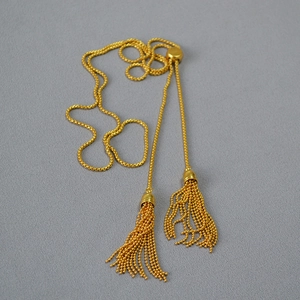 Detail of adjustable gold slider and double tassel chain on a long fringe necklace