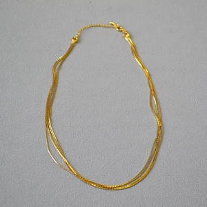 Detail view of multi-layered thin gold chains with lobster clasp and extension link