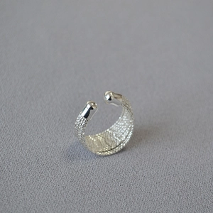 Bague ouverte moderne texture maille argentée avec perles polies sur tissu gris épuré