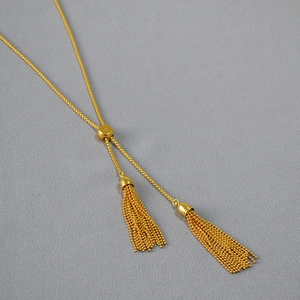 Close-up of golden adjustable Y-necklace with elegant double metal tassel pendants