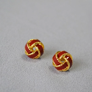Gros plan de boucles d'oreilles en émail rouge avec nœud torsadé doré chic