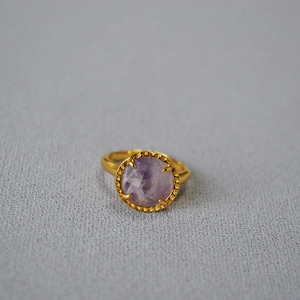 Detailed macro of a gold vintage ring featuring a faceted purple natural stone inlay