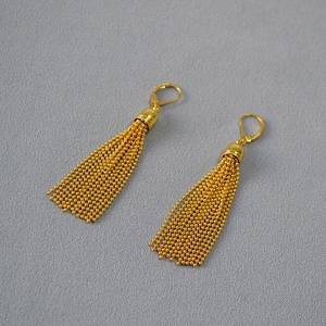 Detail of golden tassel earrings with fine metal bead chains and leverback hooks