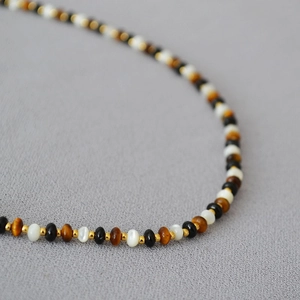 Macro shot of tiger eye stone, pearl, and black agate beads on a vintage necklace
