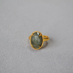 Detailed close-up of oval green labradorite stone with gold-plated beaded edge bezel ring