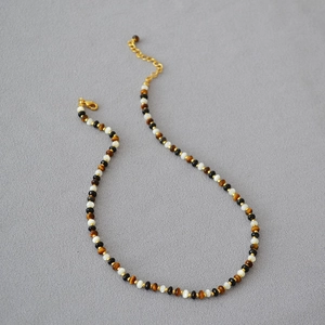 Macro view of beads featuring tiger eye, black agate, and mother of pearl with golden accents