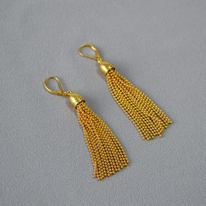 Detailed macro view of golden fringe pendants featuring multiple fine beaded metal chains