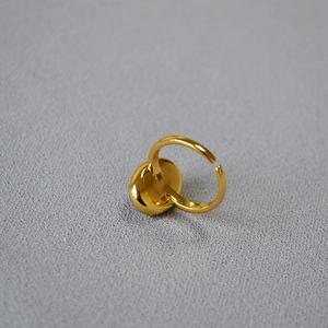 Detail of a minimalist gold-plated brass adjustable ring on a grey fabric texture