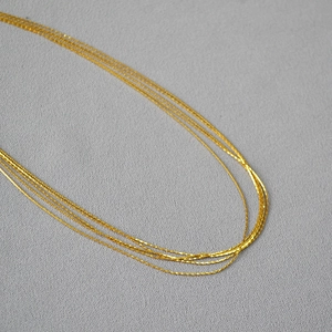 Close-up of multi-layer gold wire necklaces showing delicate sparkling texture and layers