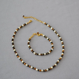 Detail of beaded necklace with tiger eye, onyx, and mother of pearl shells set in gold