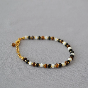 Close-up of beaded necklace with tiger eye, onyx, and gold spacers with adjustable clasp