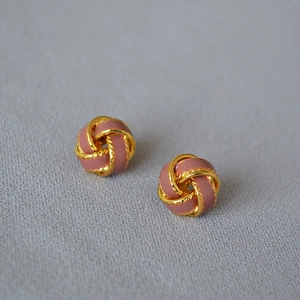 Détail de boucles d'oreilles nœud plaquées or avec émail rose et bordure torsadée