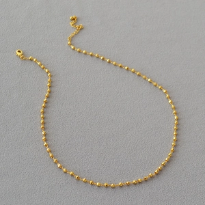 Détail du collier à billes dorées facettées avec fermoir mousqueton et chaîne d'extension