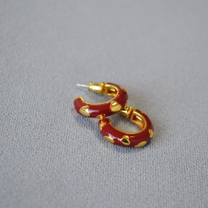 Vintage red enamel heart earrings with gold plating on textured fabric background