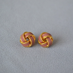 Gros plan de boucles d'oreilles nœud torsadé vintage avec dorure et émail rose poudré