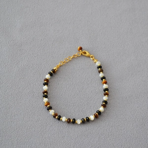 Detail of beaded necklace with tiger eye stone, black agate, and gold lobster clasp