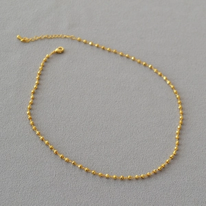 Collier minimaliste en perles de laiton plaqué or facettées avec fermoir sur tissu gris
