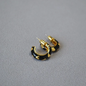Handmade enamel C-shaped hoop earrings with gold heart pattern on black background