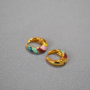 Detailed close-up of chunky gold-plated hoop earrings with colorful spiral enamel stripes