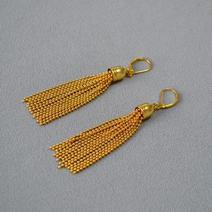 Macro view of golden bead chain tassels and hook clasp on vintage minimalist earrings