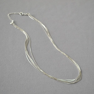 Close-up of minimalist multi-layer silver necklaces with delicate fine chain link texture