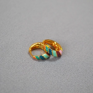 Detailed macro view of colorful enamel striped pattern on gold-plated hoop earrings