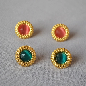 Détail de boucles d'oreilles rétro avec bordure dorée torsadée et pierres gemmes