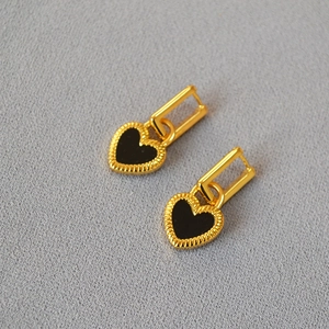 Close-up of gold-plated heart-shaped black agate earrings with vintage textured borders