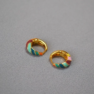 Close-up of rainbow enamel gold-plated brass hoop earrings with vibrant colorful glaze