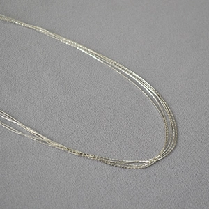 Macro detail of silver multi-layered thin chain necklace with fine metallic texture