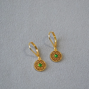 Vue détaillée de boucles d'oreilles vintage en or avec dentelle creuse et gemmes vertes