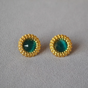 Gros plan sur boucles d'oreilles pierre verte avec bordure torsadée dorée style vintage