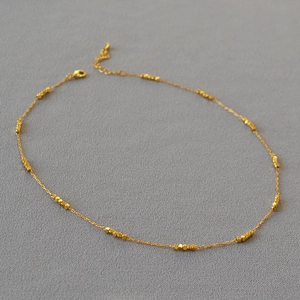 Detail of gold plated brass necklace with faceted square beads and lobster clasp closure