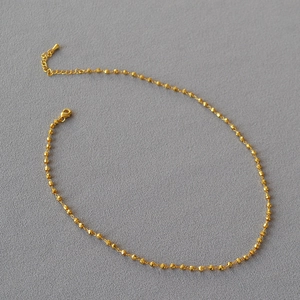 Collier en perles de laiton plaqué or facetté avec fermoir réglable sur fond gris