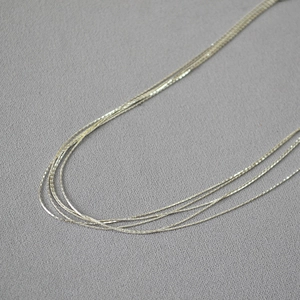 Detail of silver multi-layer thin chain necklace with minimalist woven metal texture