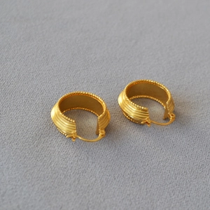 Detail of vintage ribbed gold earrings with intricate beaded edges and a textured finish