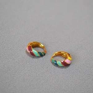 Macro detail of spiral brass earrings with colorful enamel glaze and gold plating