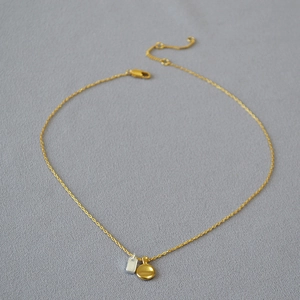 Macro shot of minimalist gold and silver geometric pendants on a fine brass chain