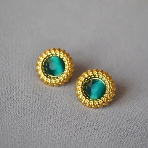 Gros plan de boucles d'oreilles vintage en or torsadé avec pierres œil-de-chat vert