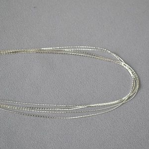 Macro detail of multi-layered minimalist fine silver chain links with polished finish