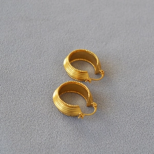 Macro shot of gold-plated brass C-hoop earrings with ribbed texture and beaded edges