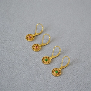 Détail de boucles d'oreilles bohèmes en dentelle fleurie avec pierres rose et verte