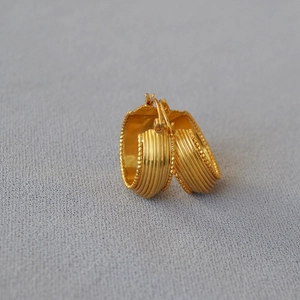 Macro detail of gold plated hoop earrings with vertical ridges and beaded edges