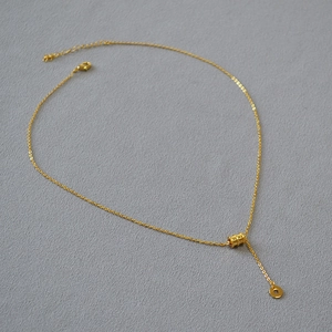 Collier élégant plaqué or avec pendentif cylindrique et détails de texture raffinés