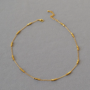 Minimalist gold plated brass choker with faceted square beads and lobster clasp on grey fabric
