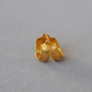Detailed macro of gold plated brass hoop earrings with vintage striped texture and beaded edges