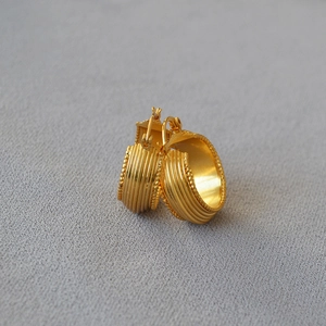 Detail view of gold hoop earrings with vertical stripes and delicate beaded edges