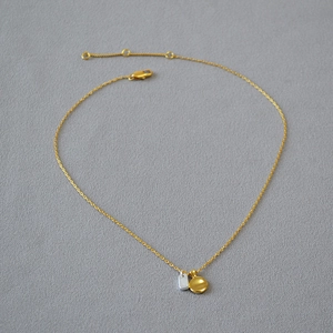 Detailed close-up of a gold-plated brass chain with silver and gold duo-tone pendants